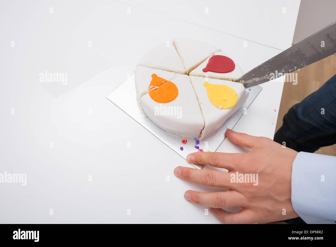 Immagine ritagliata dell uomo il taglio di torta di compleanno a tavola Foto Stock