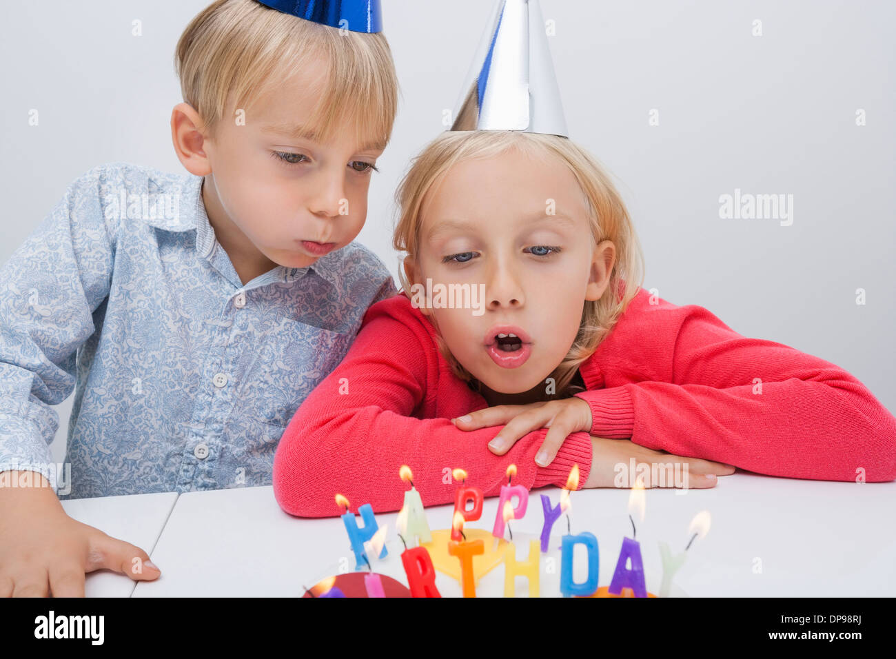 Fratello e Sorella di soffiaggio candele di compleanno a tavola in casa Foto Stock