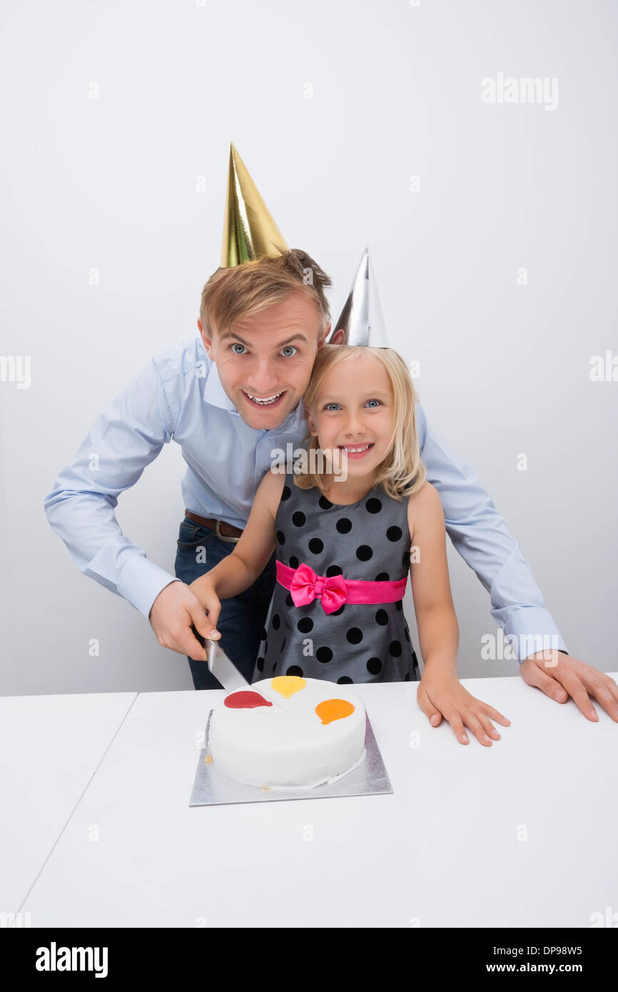 Ritratto di felice padre e figlia il taglio di torta di compleanno a tavola Foto Stock