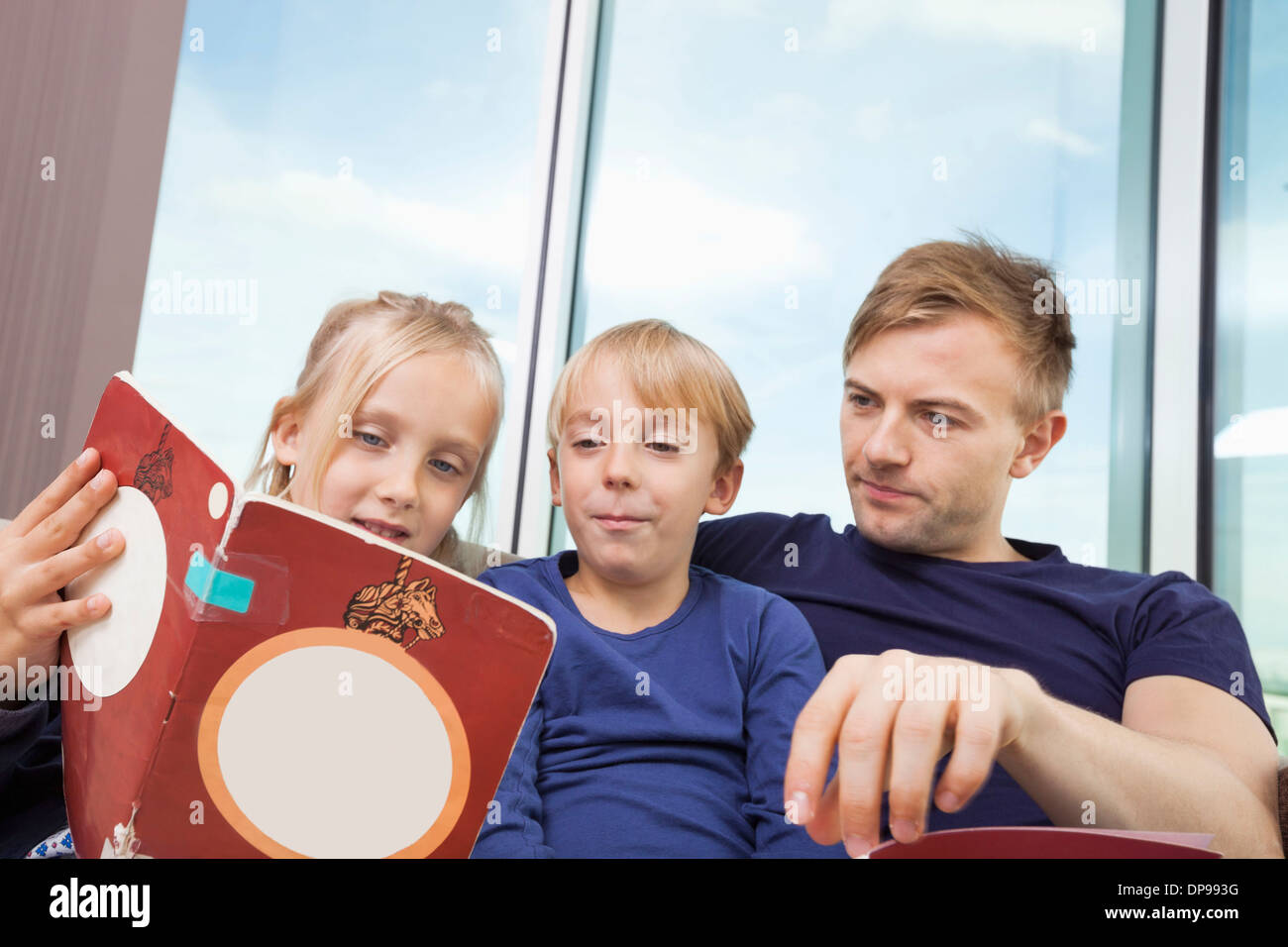 Padre e figli lettura storybook a casa Foto Stock