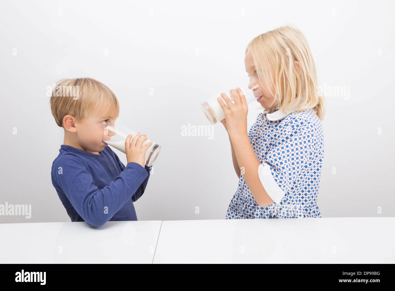 I bambini a bere latte mentre guardando ogni altro Foto Stock
