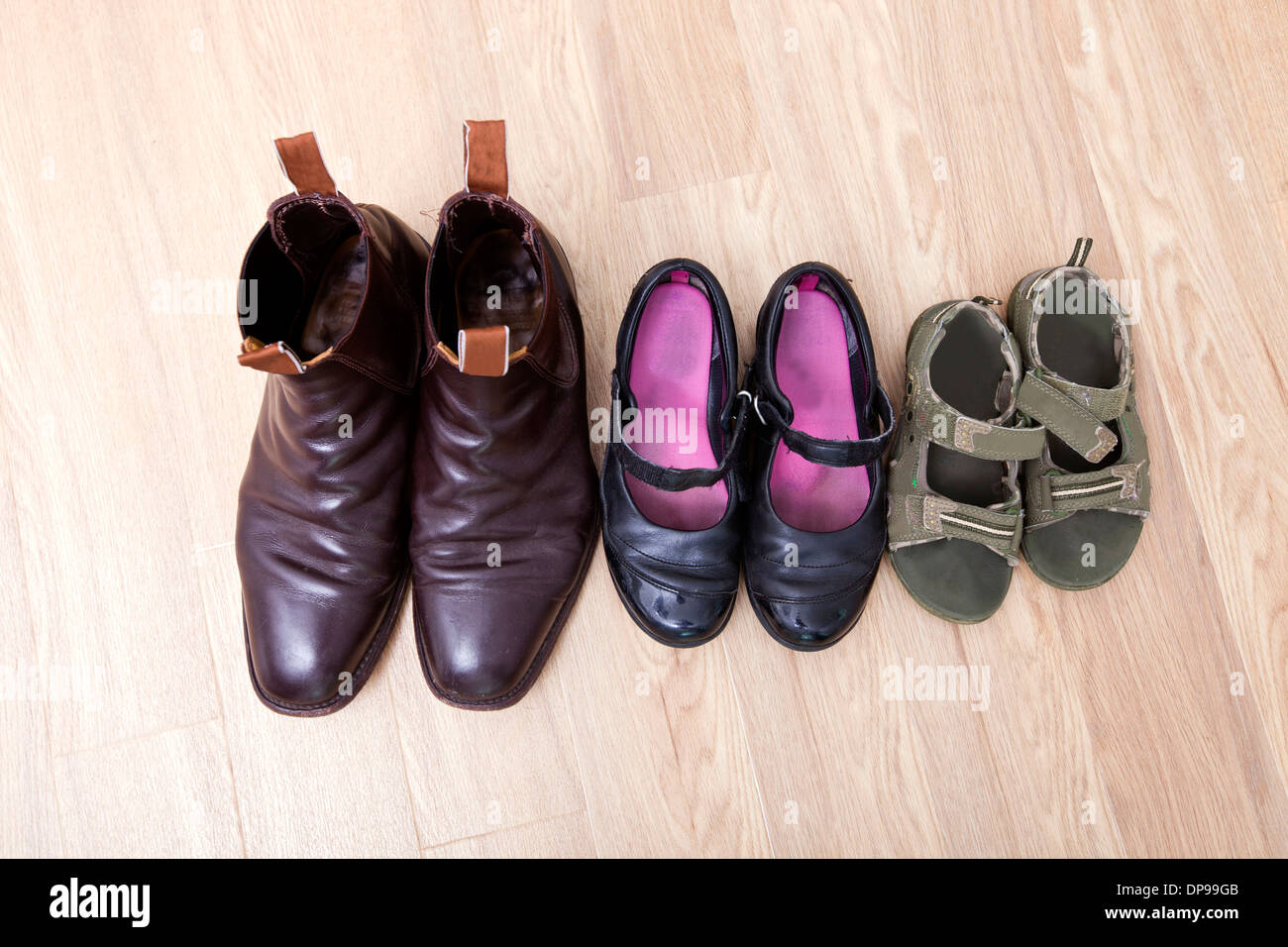 Elevato angolo di visione della famiglia scarpe messo in fila sul pavimento di legno duro Foto Stock