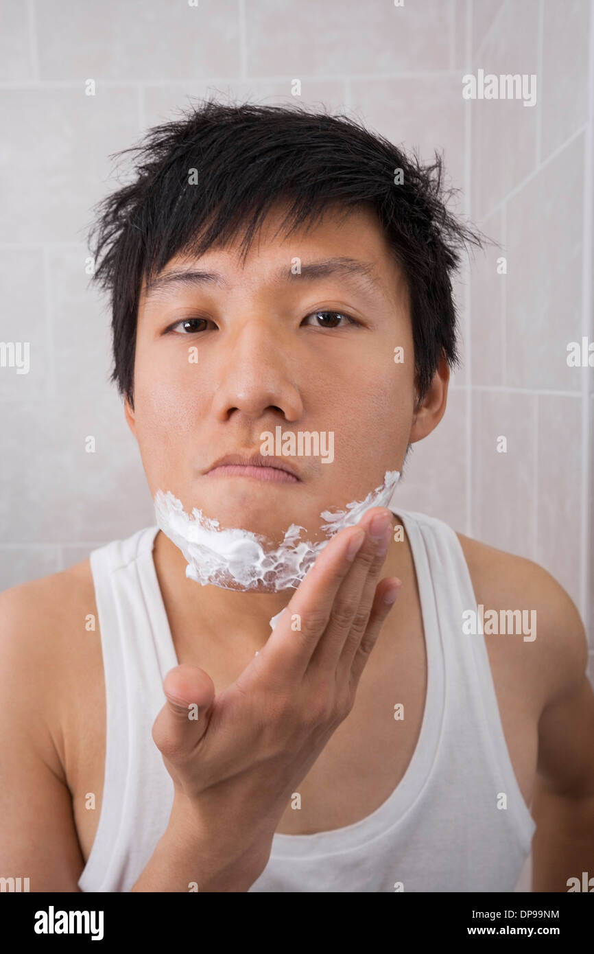 Ritratto di metà uomo adulto Applicare schiuma da barba sulla faccia nella stanza da bagno Foto Stock