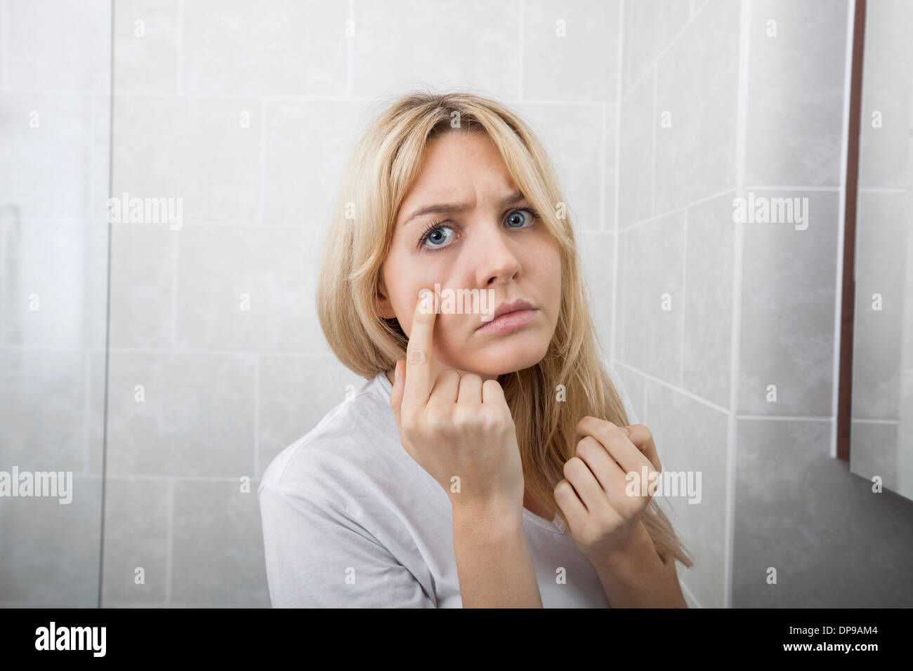Giovane donna esaminando brufoli sulla faccia nella stanza da bagno Foto Stock
