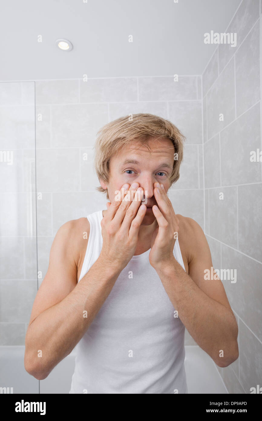 Ritratto di uomo controllo per le rughe sul suo volto nella stanza da bagno Foto Stock
