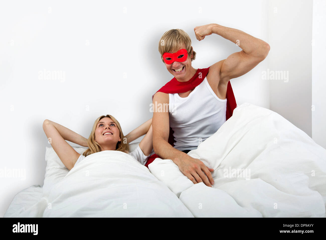 Ritratto di uomo in costume da supereroe con la donna sul letto Foto Stock