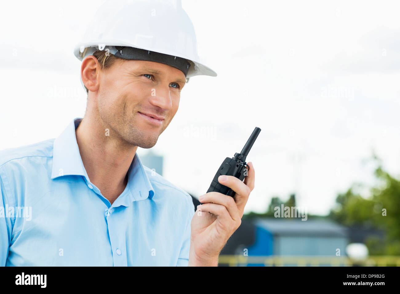 Architetto sorridente holding walkie-talkie al sito in costruzione Foto Stock