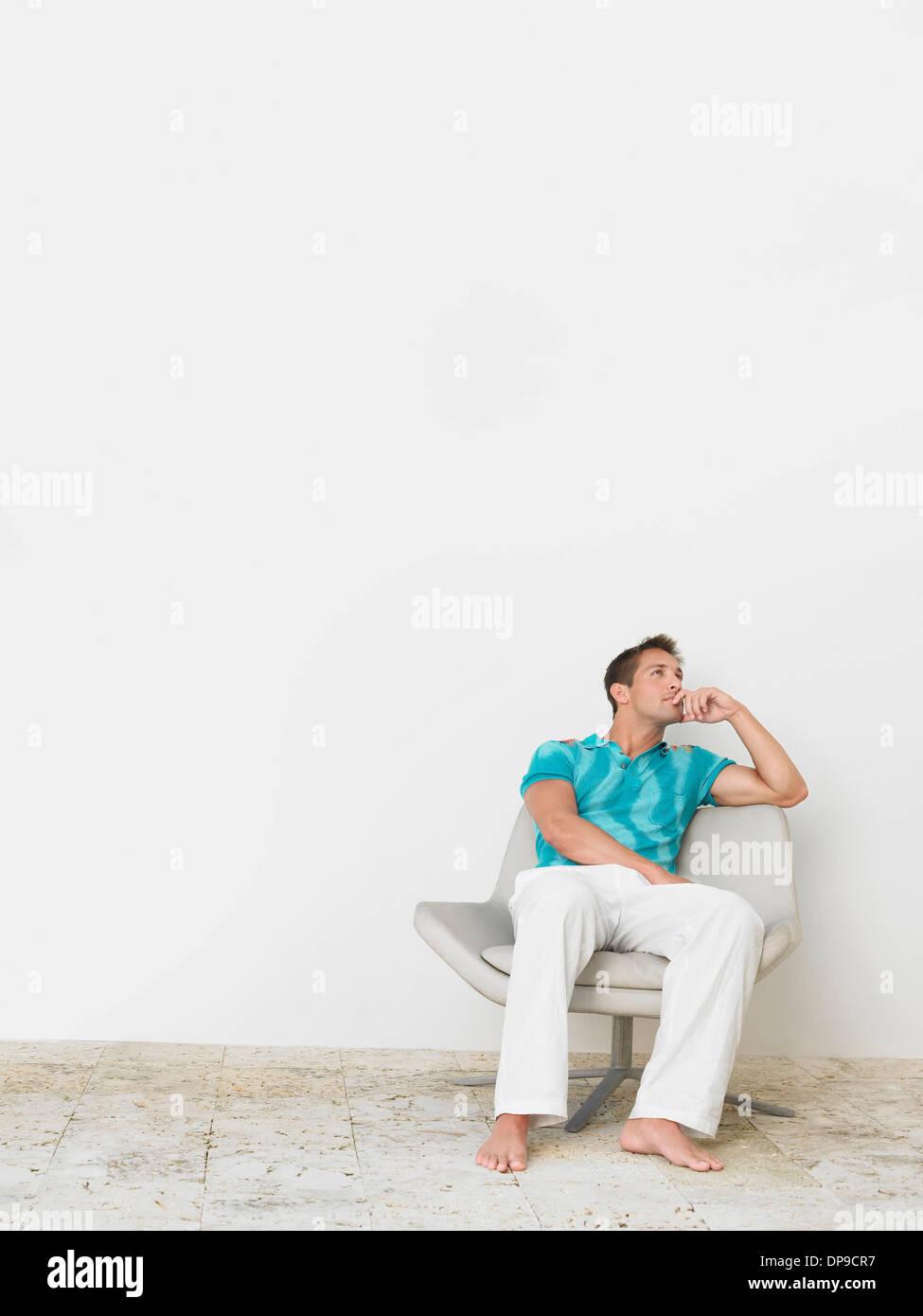 Lunghezza completa di pensosa giovane uomo seduto su una sedia Foto Stock