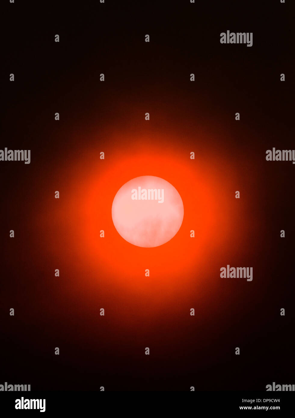 Il fumo proveniente da incendi boschivi crea un insolito eerie bagliore arancione al tramonto. Foto Stock