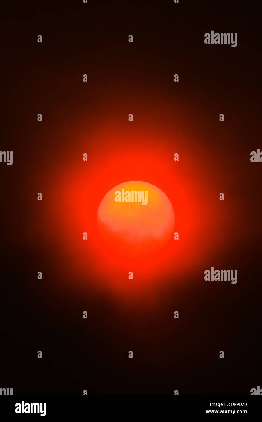 Il fumo proveniente da incendi boschivi crea un insolito eerie bagliore arancione al tramonto. Foto Stock