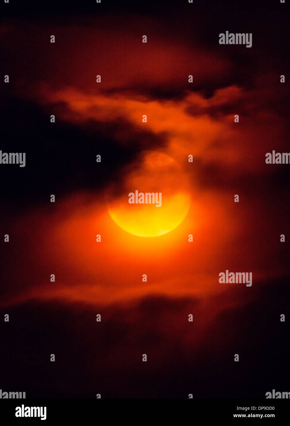 Il fumo proveniente da incendi boschivi crea un insolito eerie bagliore arancione al tramonto. Foto Stock