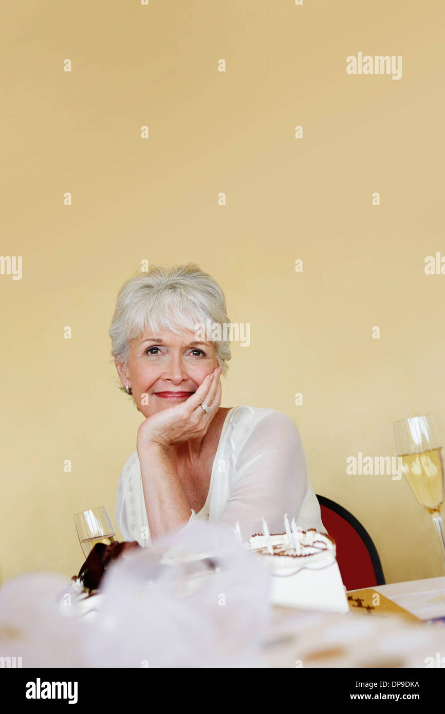 Donna seduta in mano sul mento in un partito di pensionamento Foto Stock