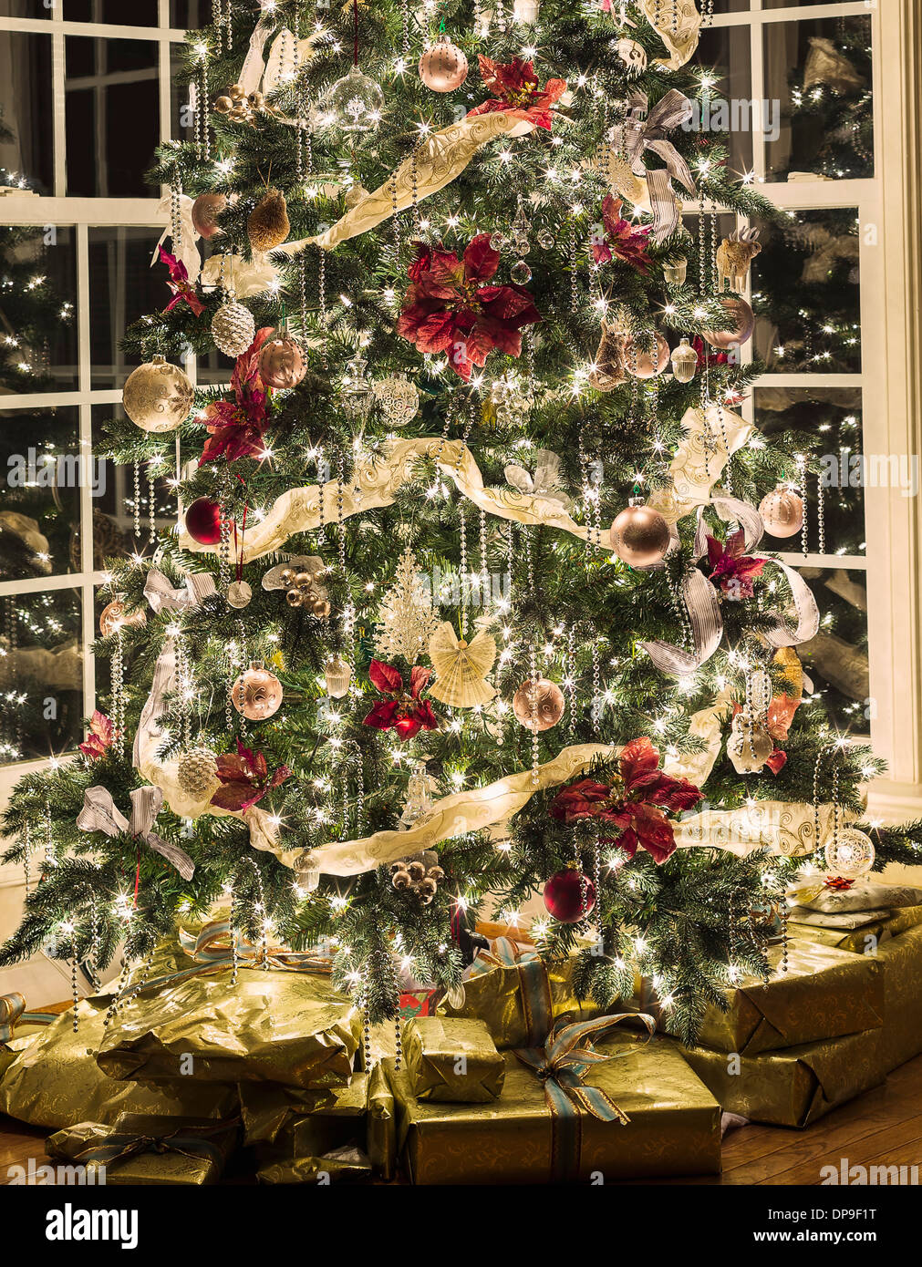 Albero di natale con luci e decorazioni e regali di Natale al di sotto in una casa di soggiorno Foto Stock