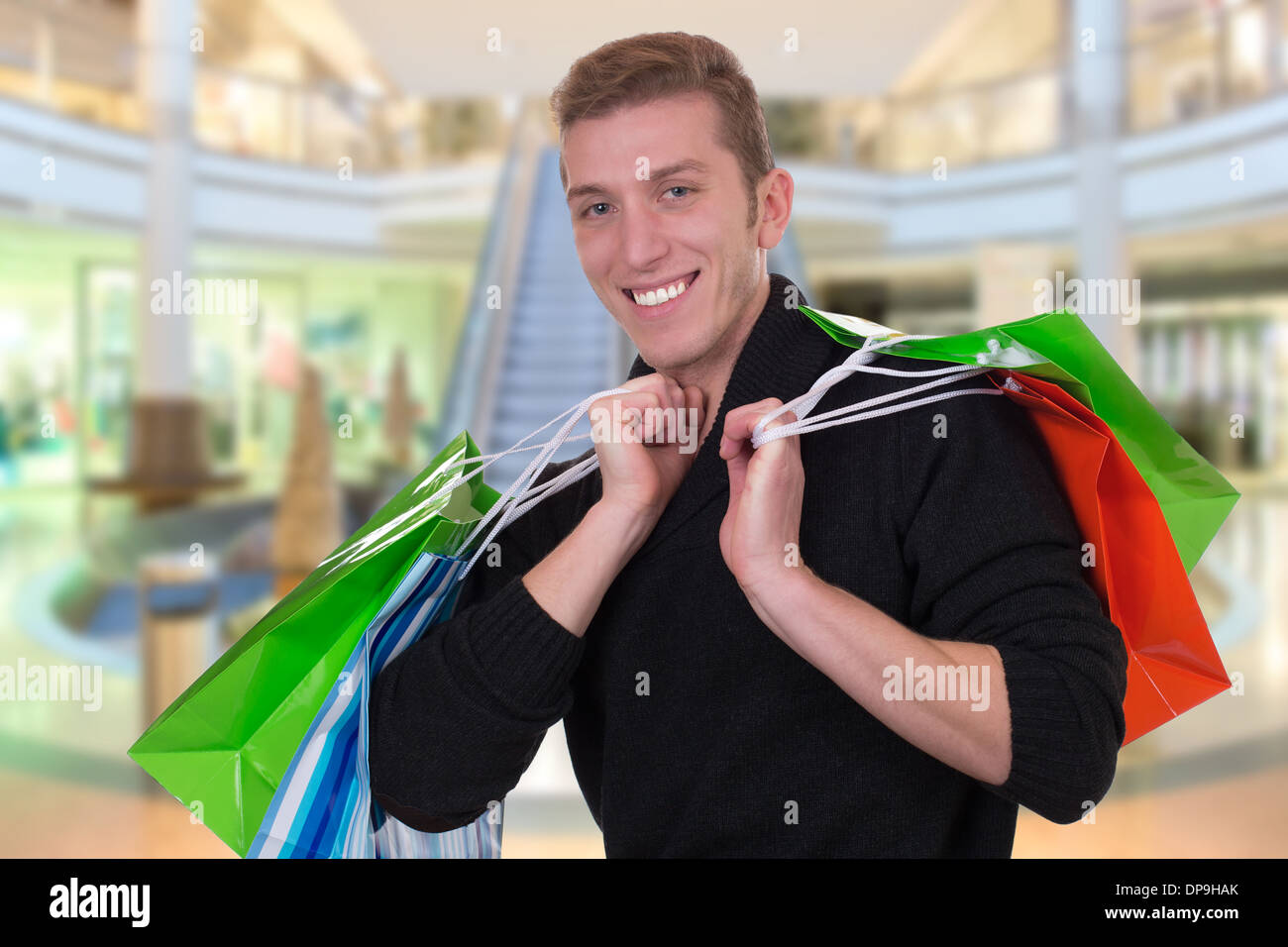 Sorridente giovane uomo di shopping o di acquisto in un negozio o centro commerciale Foto Stock