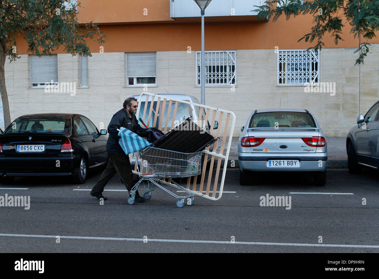 Un junkman spinge il suo carrello dove egli sceglie tra la posta indesiderata in rame, ferro e acciaio per seel su local junkyards, Mallorca, Spagna Foto Stock