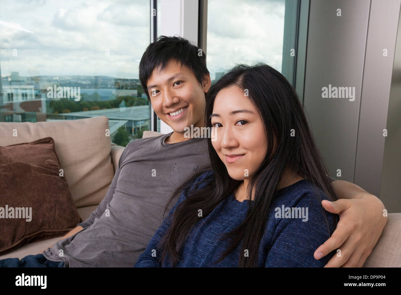 Ritratto di felice amare giovane seduto sul divano di casa Foto Stock