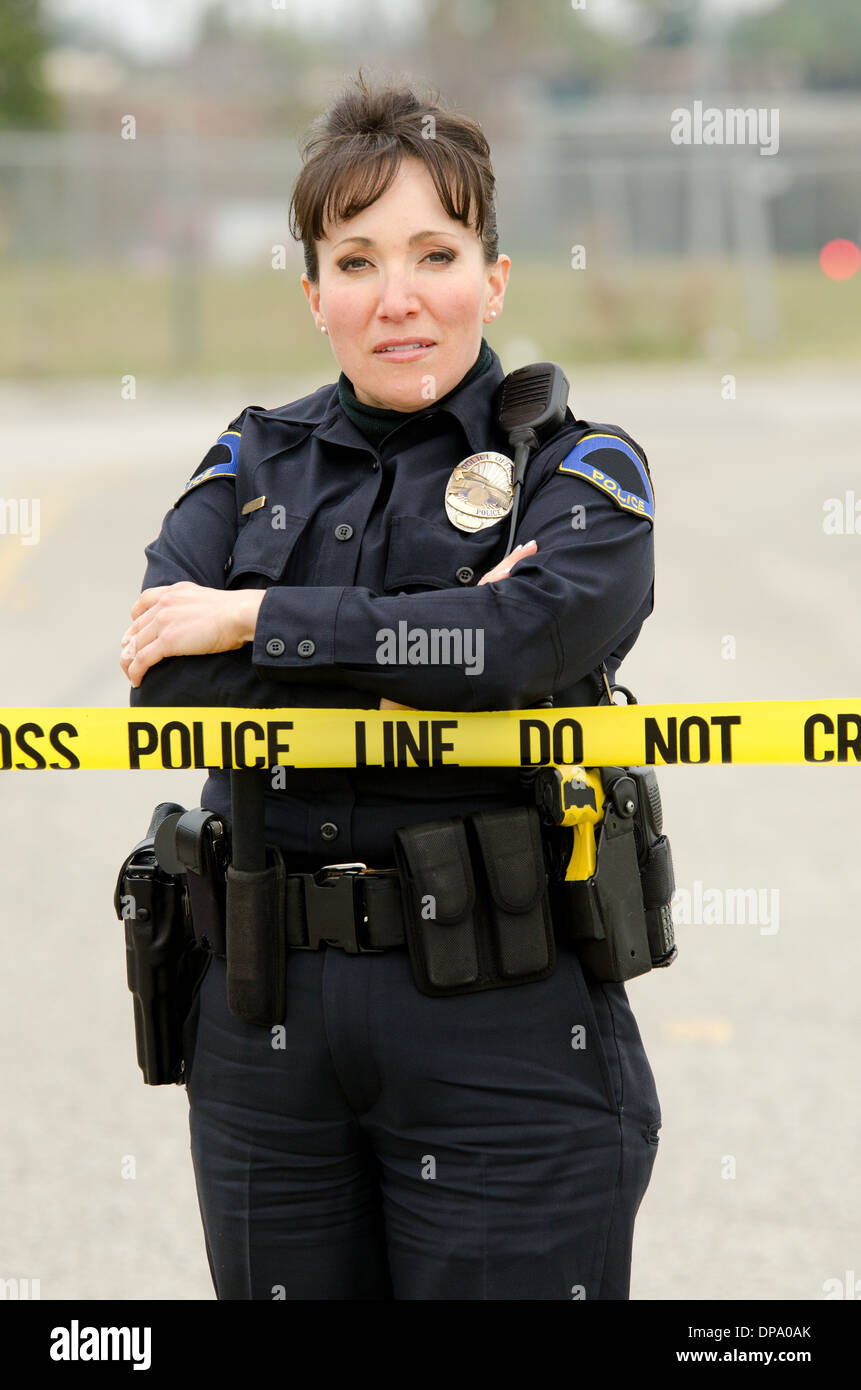 Una femmina ispanica funzionario di polizia sta in piedi in una scena del crimine. Foto Stock