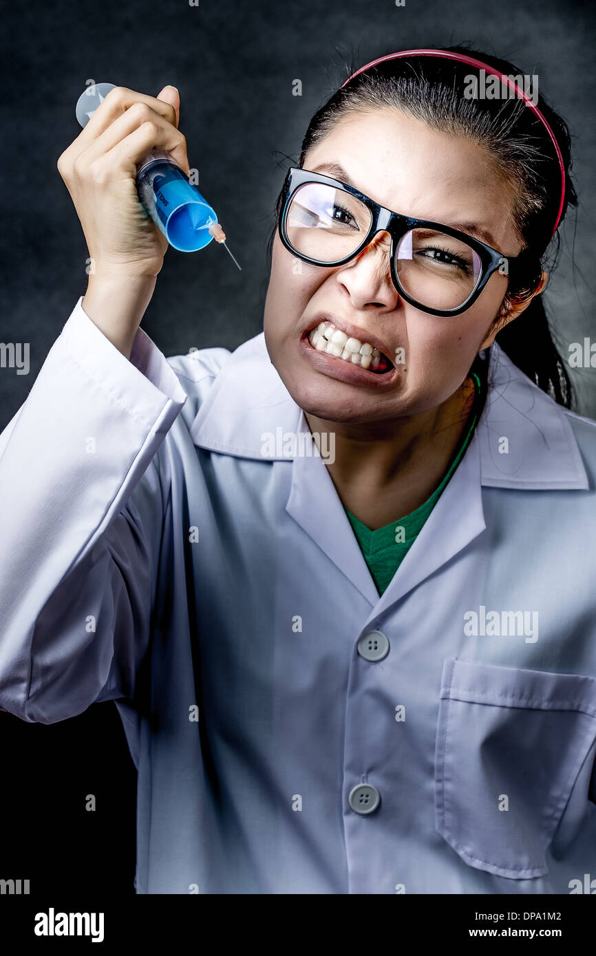 Arrabbiato crazy asian medico con una siringa riprese in studio Foto Stock