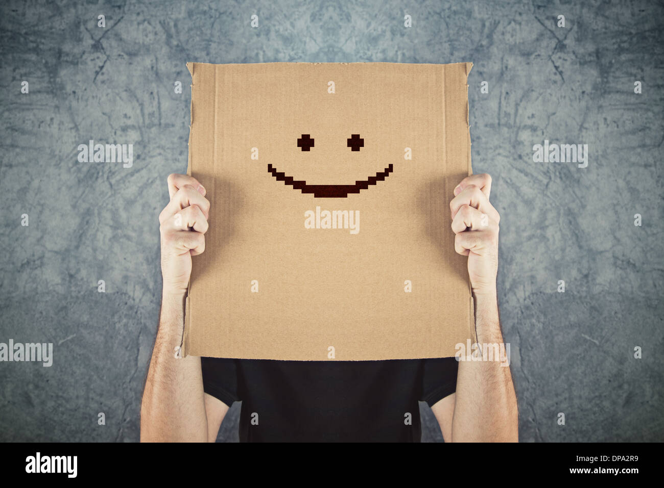 Uomo con carta di cartone con happy Smiley face stampato su. La felicità e la gioia del concetto. Foto Stock