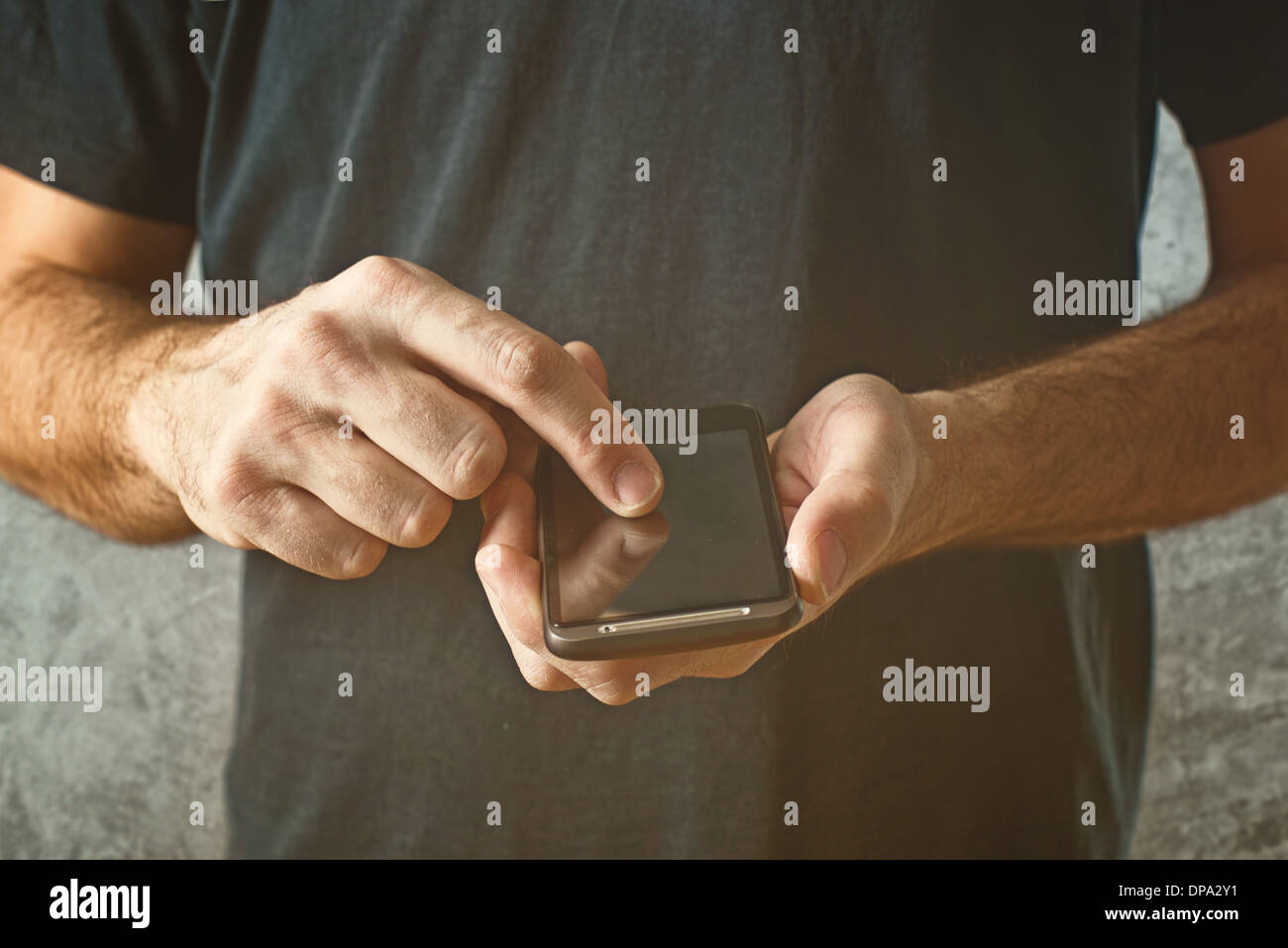L'uomo la digitazione di un messaggio di testo sul suo smart phone, concentrarsi sulle mani e il dispositivo telefonico. Foto Stock