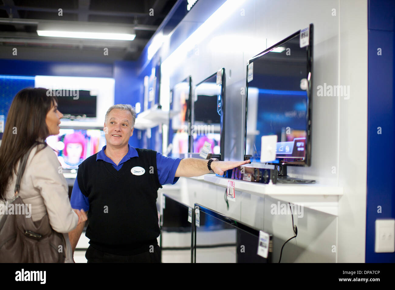 Donna che guarda la TV a schermo piatto in showroom Foto Stock