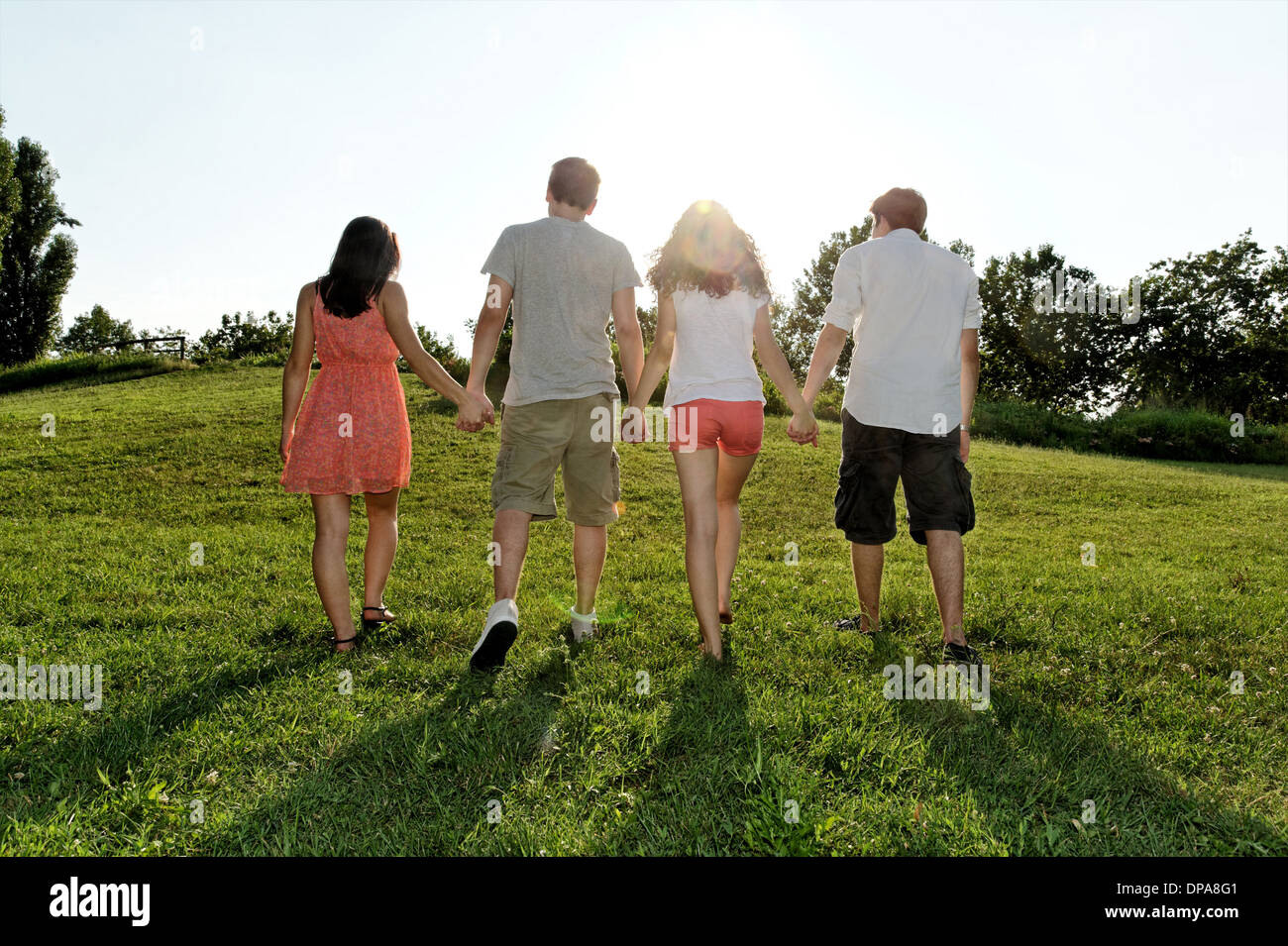 Un gruppo di giovani adulti a piedi e tenendo le mani Foto Stock
