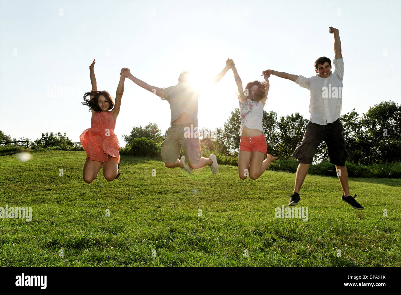 Un gruppo di giovani adulti jumping metà aria nel campo Foto Stock