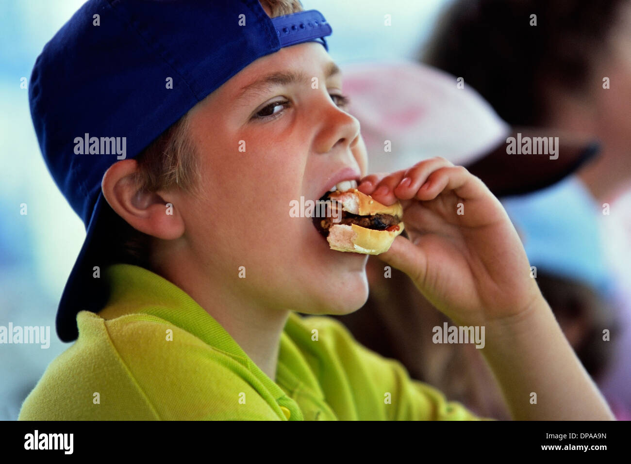 Caucasian tween boy mangiare un hamburger di manzo Foto Stock