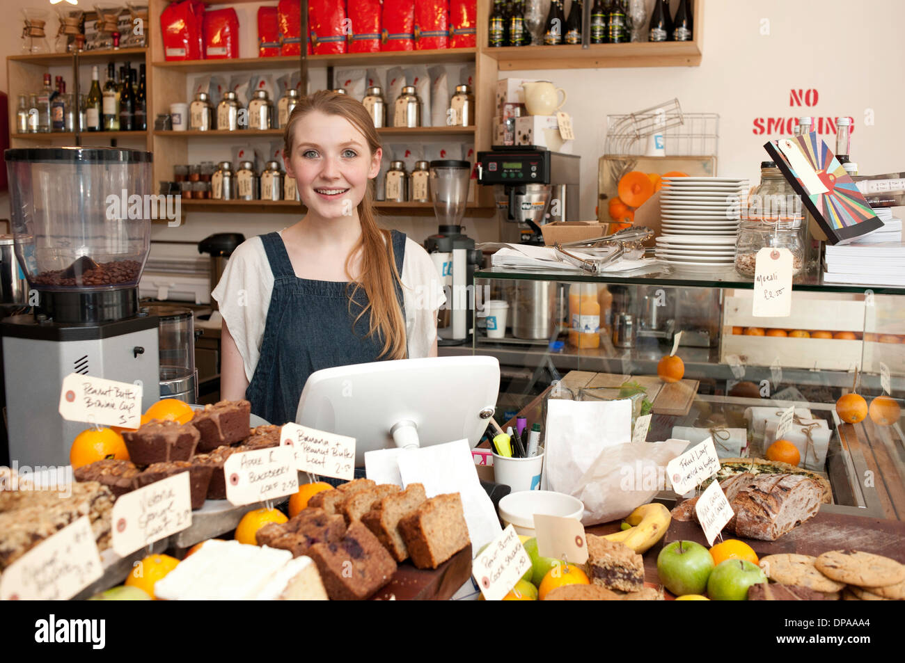 Giovane donna dietro il bancone cucina in cafe Foto Stock