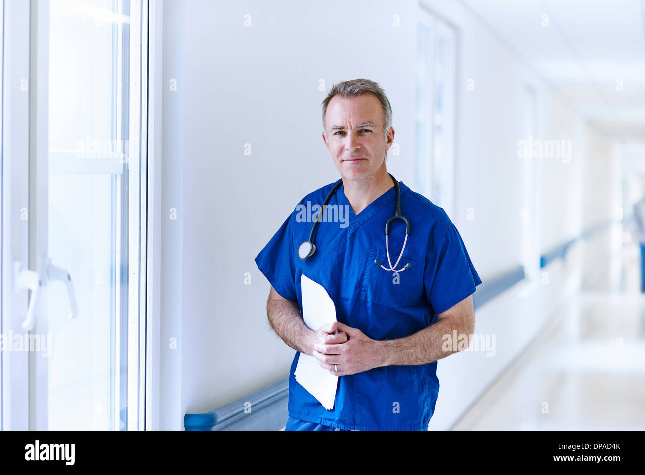 Dottore in piedi nel corridoio tenendo i record medici Foto Stock