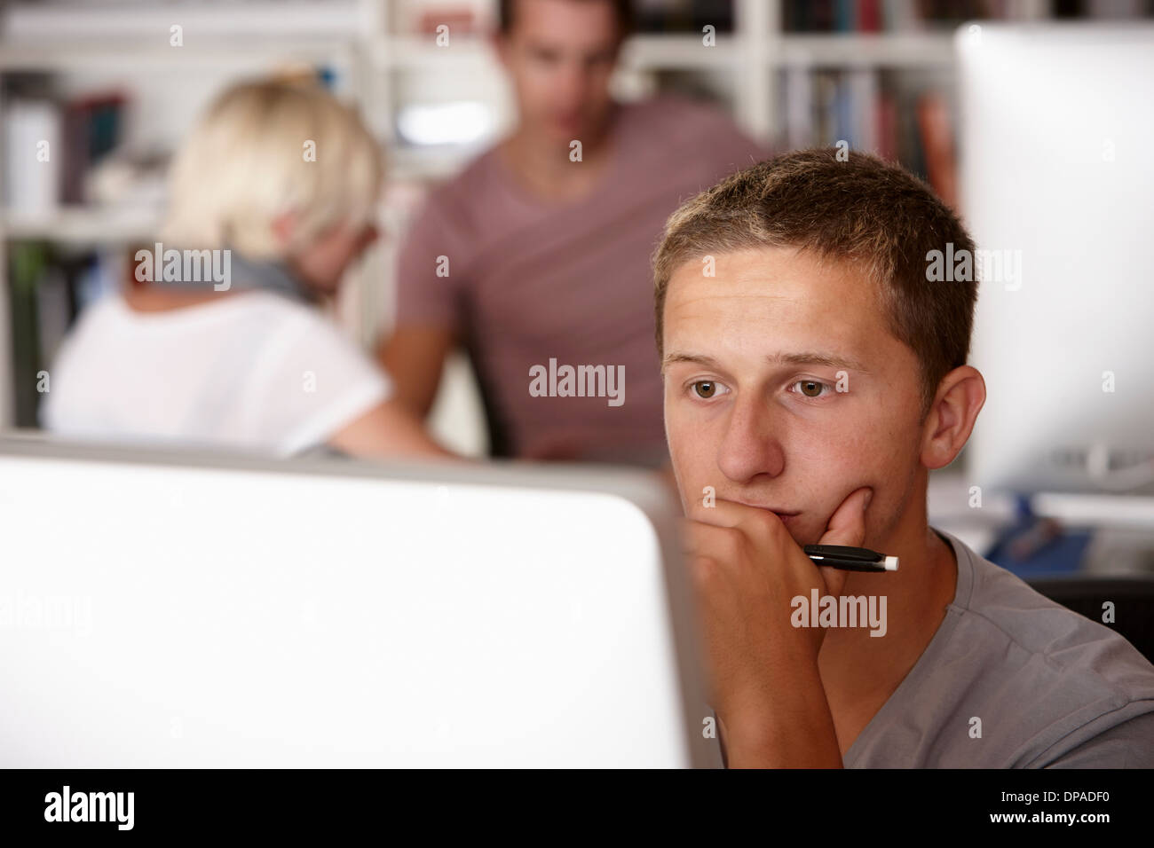Giovane uomo utilizzando computer, mano sul mento Foto Stock