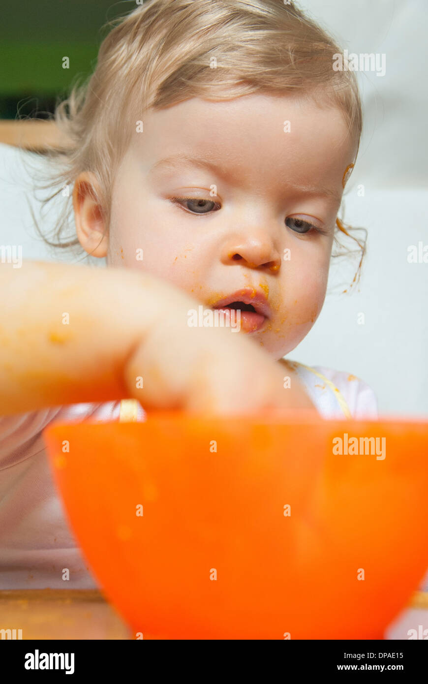 Bambina con la mano in Orange Bowl Foto Stock