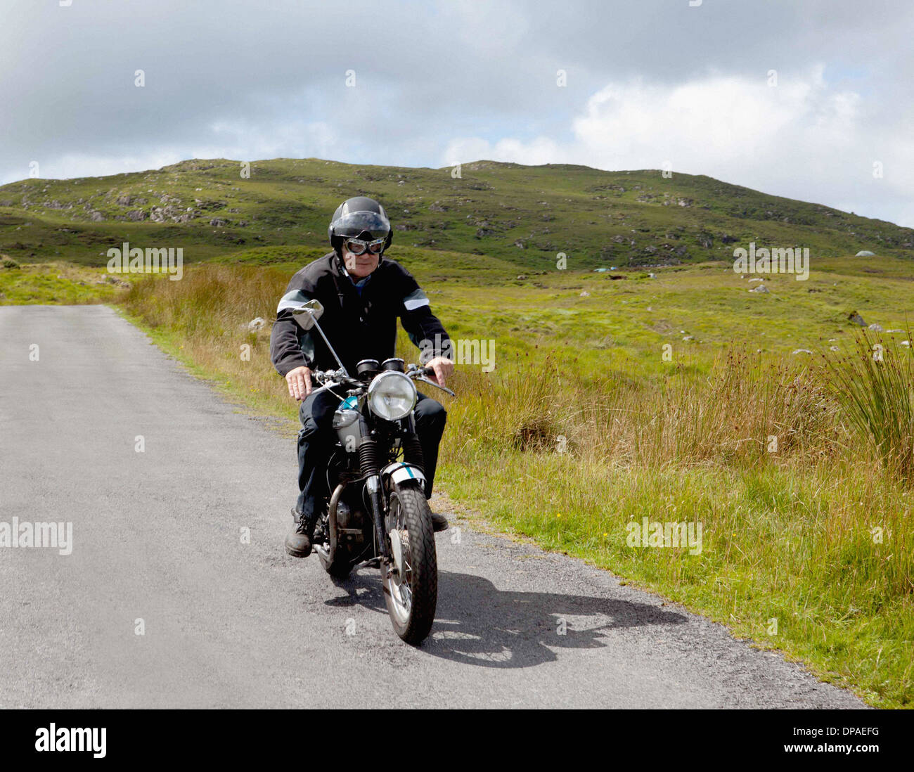 Maschio Senior motociclista equitazione sulla strada rurale Foto Stock