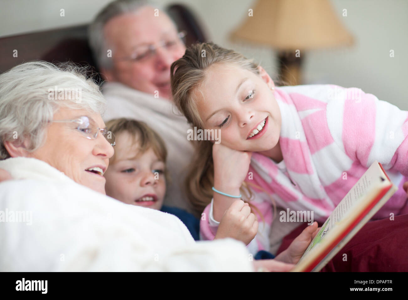 Nonni e nipoti lettura storybook nel letto Foto Stock