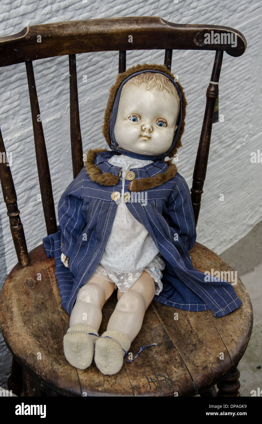 Vintage del bambino bambola seduta su una vecchia sedia al di fuori di un negozio di posta indesiderata a Edimburgo, Scozia. Foto Stock