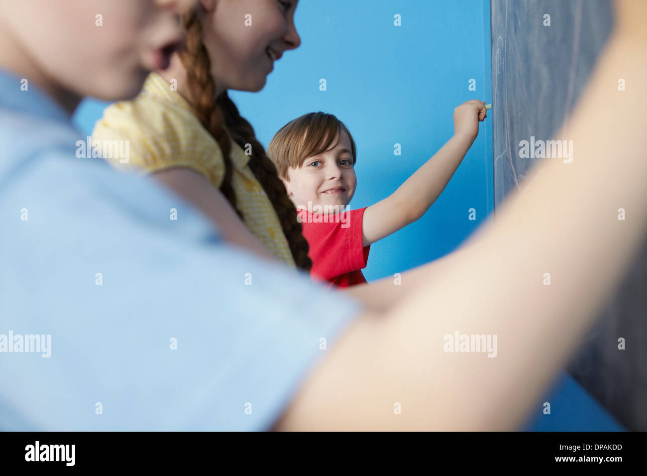 Bambini scrivere sulla lavagna, sfondo blu Foto Stock