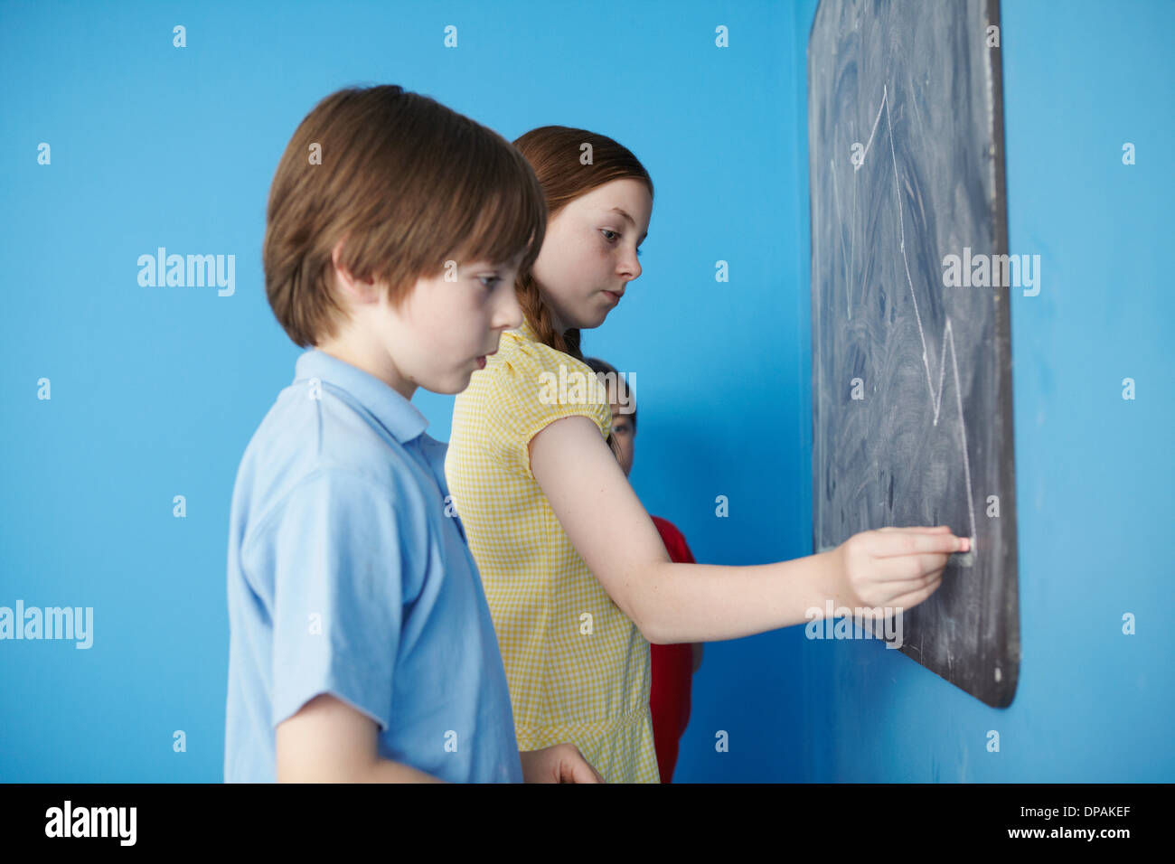 Bambini scrivere sulla lavagna, sfondo blu Foto Stock