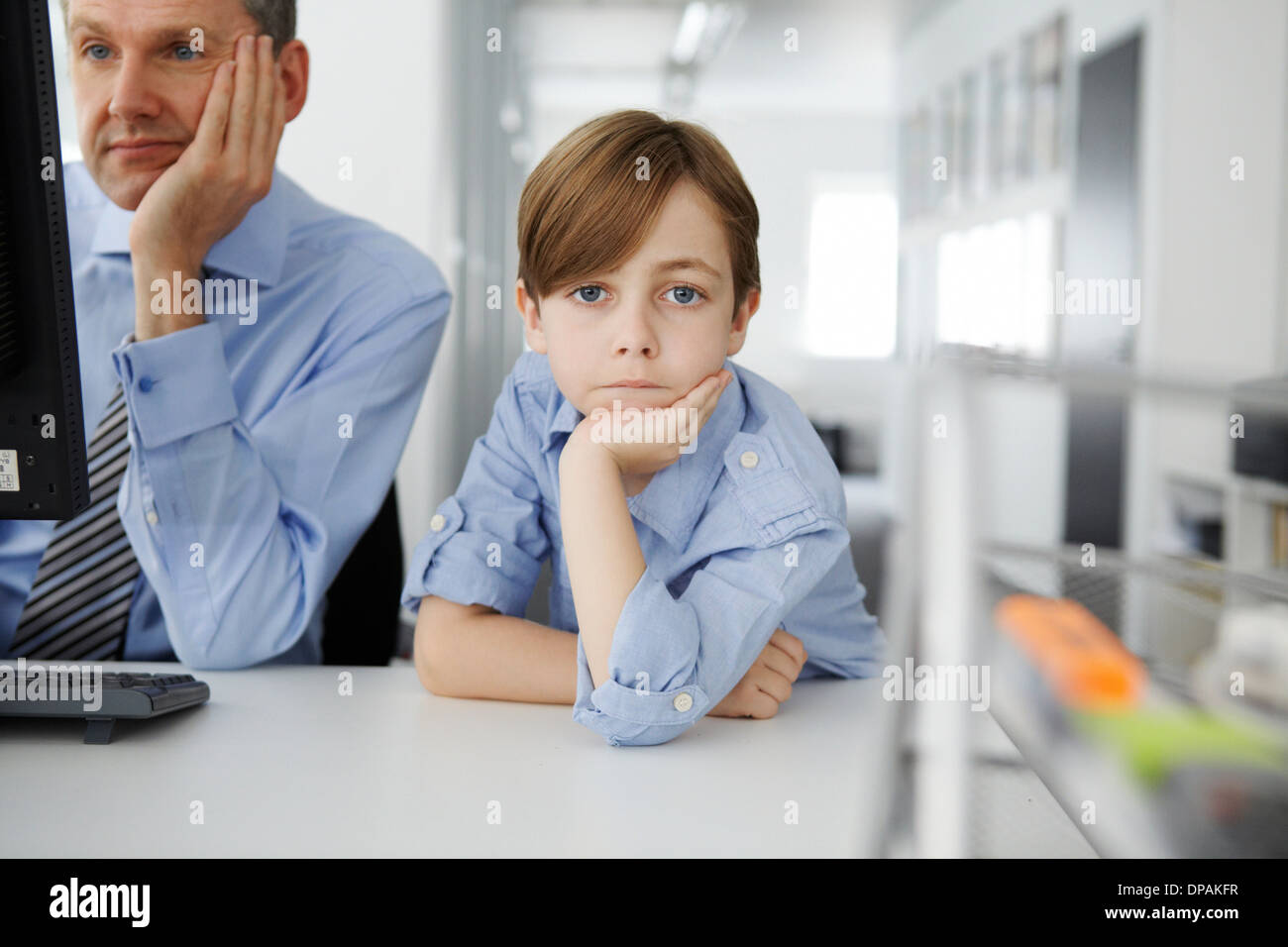 Ragazzo appoggiata sul gomito, padre tramite il computer Foto Stock