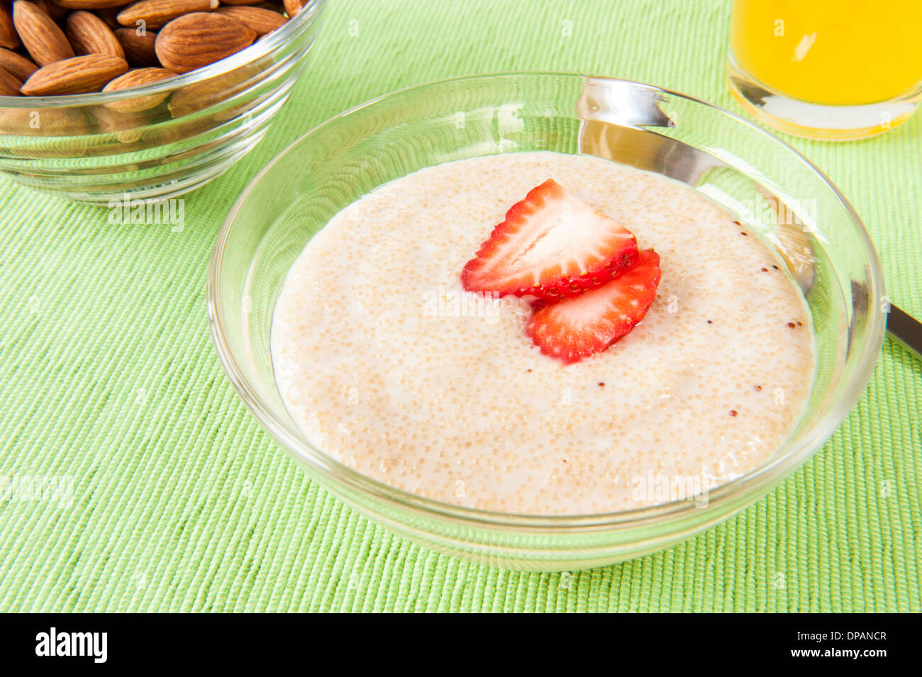 Piatto di amaranto e yogurt con mandorle crude e un bicchiere di succo di arancia Foto Stock