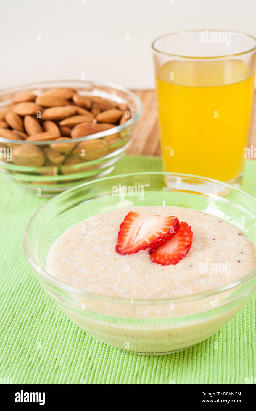 Piatto di amaranto e yogurt con mandorle crude e un bicchiere di succo di arancia Foto Stock