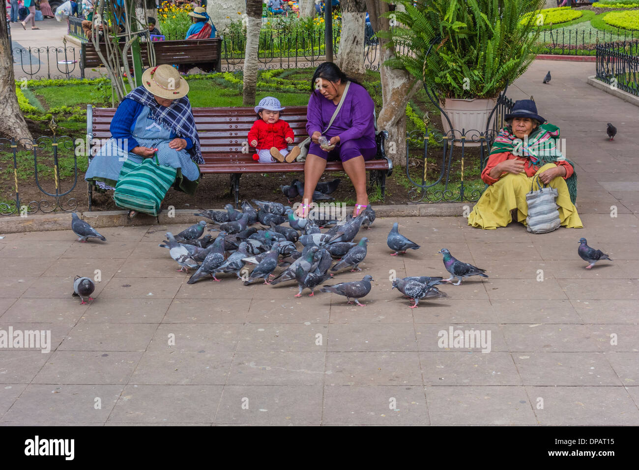 Tre donne e un bambino che alimenta i piccioni nella centrale Plaza, 25 Plaza de Mayo, in Sucre, Bolivia. Foto Stock