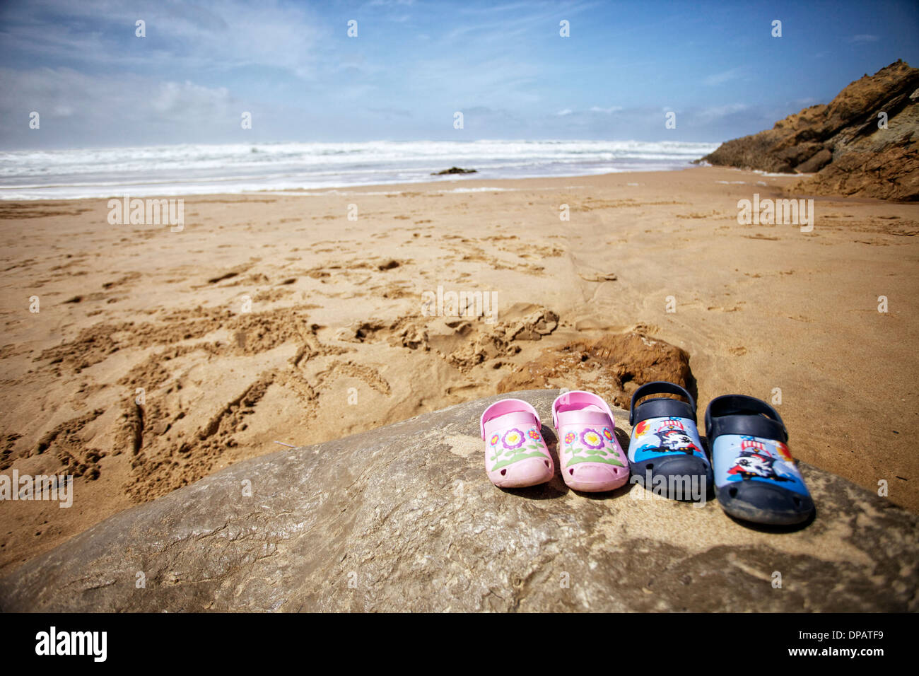 Bambini " crocs " scarpe su una roccia su una spiaggia con le onde e il  cielo blu dietro Foto stock - Alamy