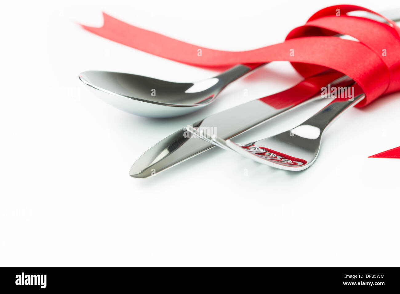 Forchetta, cucchiaio e il coltello legato con un nastro rosso isolato su sfondo bianco Foto Stock