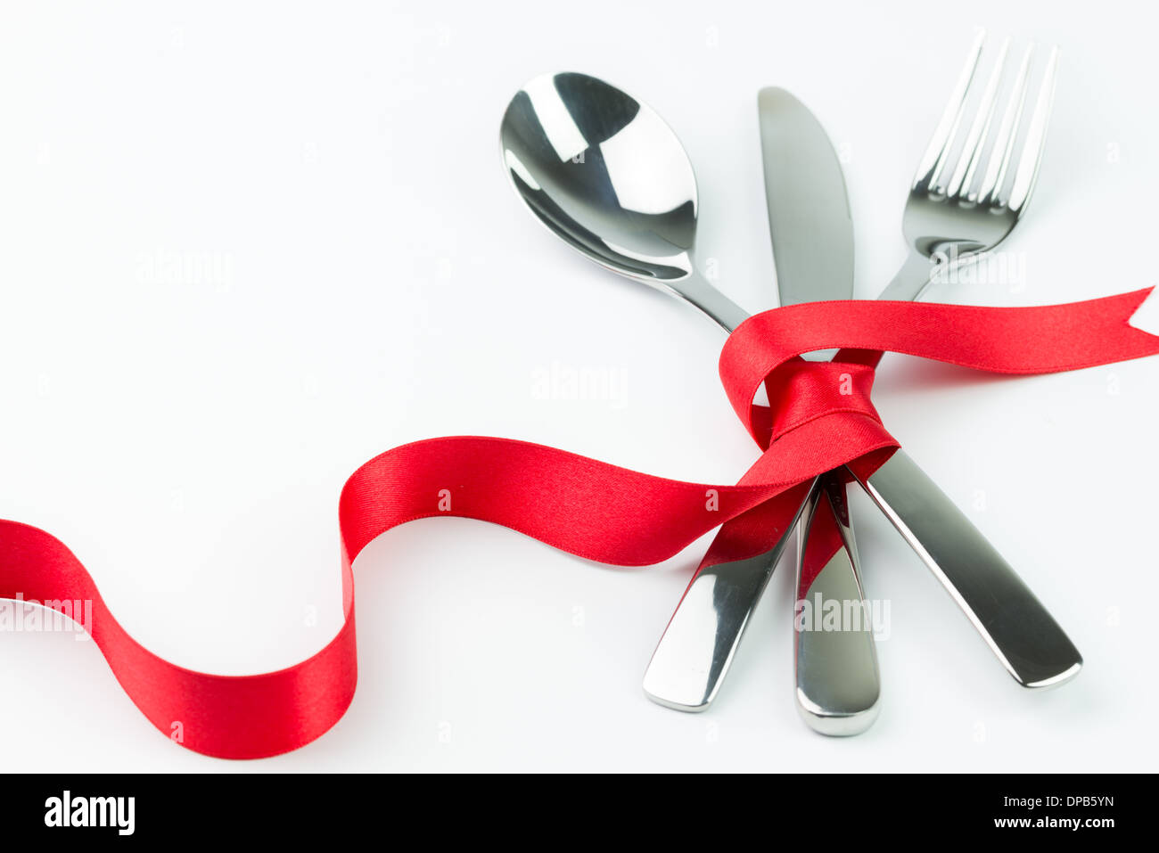 Forchetta, cucchiaio e il coltello legato con un nastro rosso isolato su sfondo bianco Foto Stock