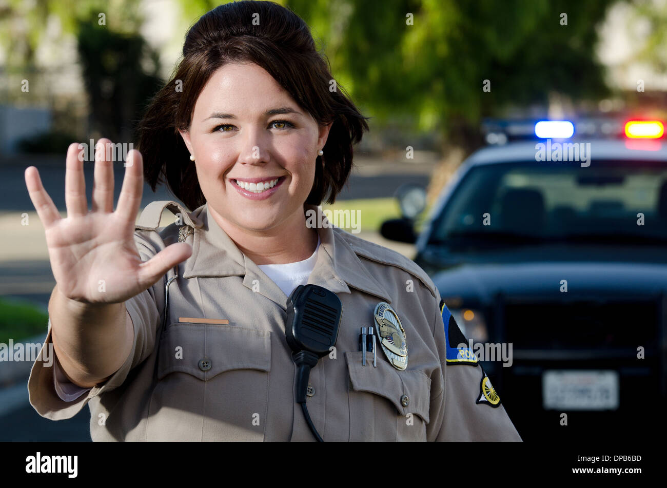 Una femmina sorridente funzionario di polizia trattiene la sua mano per ottenere il traffico per interrompere. Foto Stock