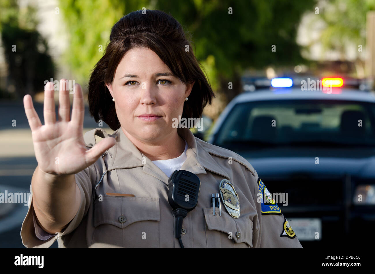Una femmina di funzionario di polizia trattiene la sua mano per ottenere il traffico per interrompere. Foto Stock