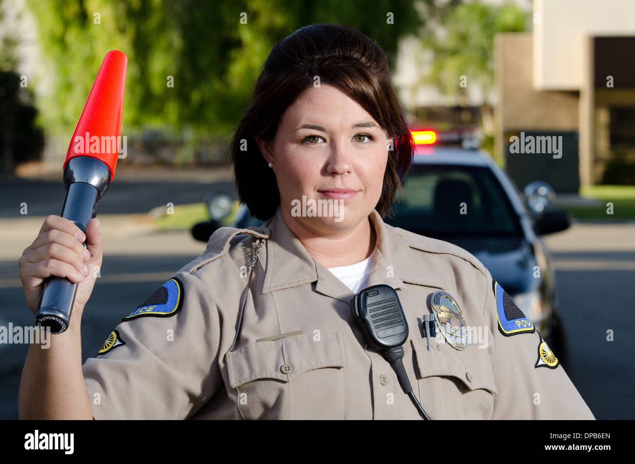 Una femmina di funzionario di polizia onde la torcia per ottenere il traffico in movimento. Foto Stock