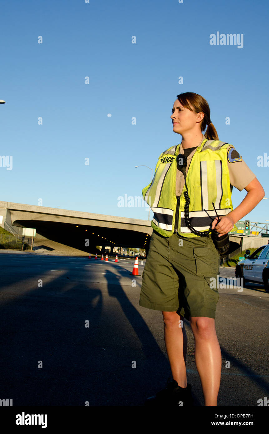 Una femmina di funzionario di polizia staring e guardando gravi durante un controllo del traffico di turno. Foto Stock