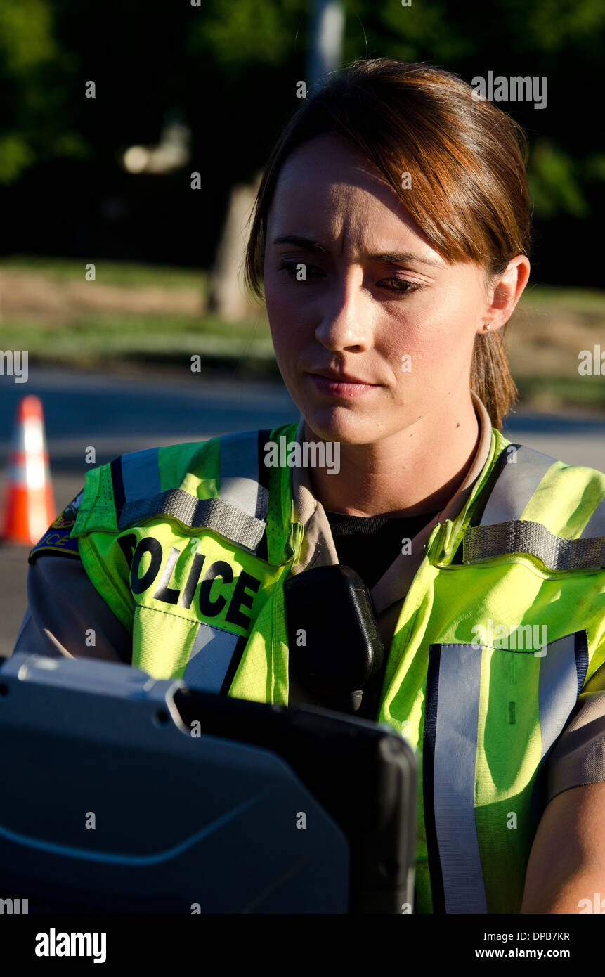 Una femmina di funzionario di polizia tipi sul suo computer portatile mentre è in corso una chiamata. Foto Stock