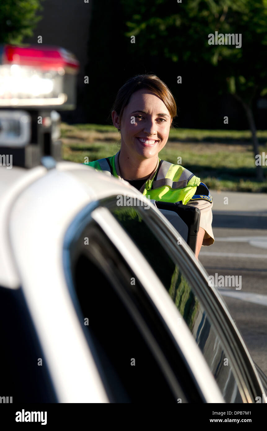 Una femmina di funzionario di polizia sorrisi durante la digitazione sul suo computer lap top. Foto Stock